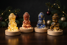 Charger l'image dans la galerie, Quatre petits Bouddhas sur socles lumineux dans une ambiance de Noël en soirée
